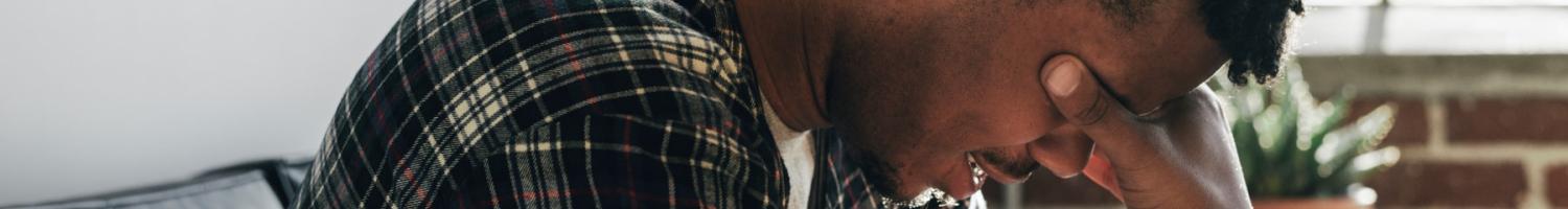 Photo of pensive black man sitting on couch