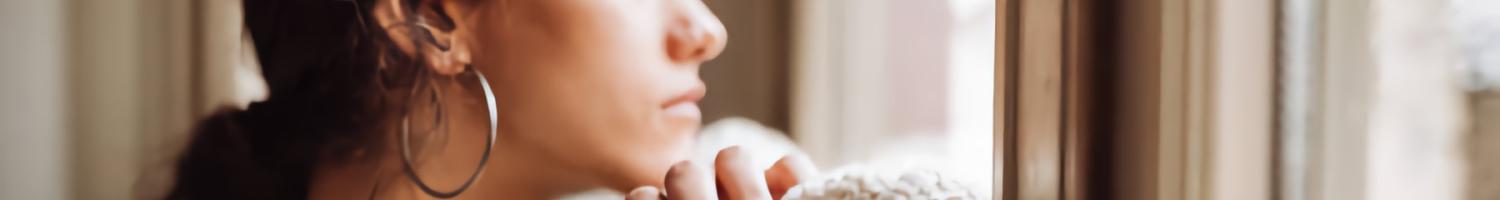 Photo of pensive woman in front of the window