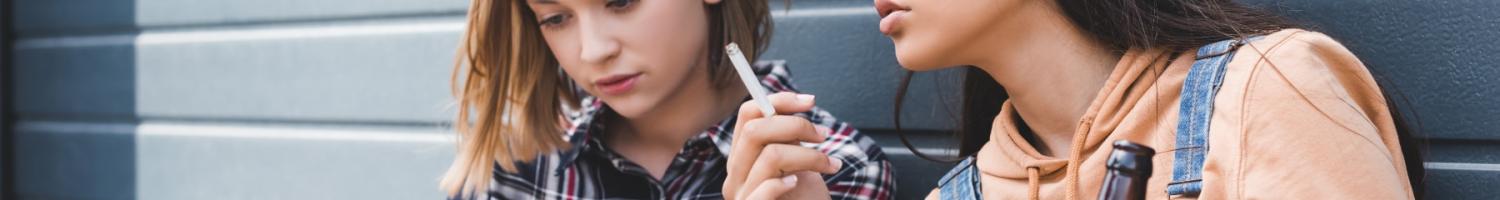 Photo of young teenage girls drinking and smoking outdoors