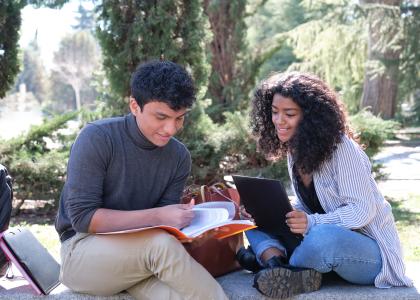 Two latino teens reading in outdoor setting