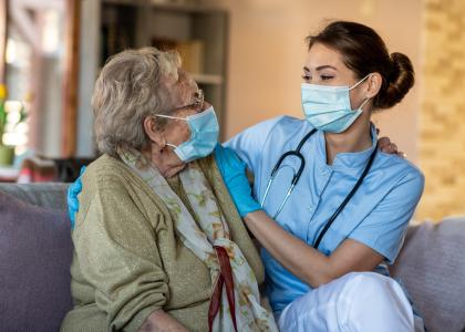 Photo of elderly woman and healthcare provider in living room