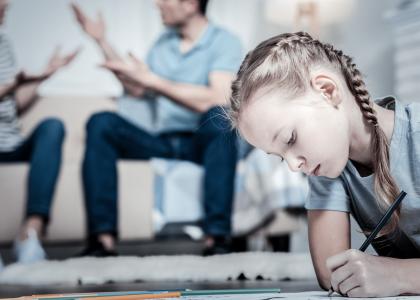 Photo of child drawing while parents argue in the background