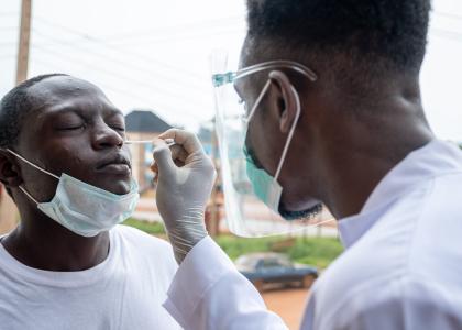 Photo of clinician nasal swabbing a man for a covid test outdoors