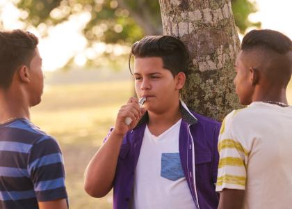 Photo of three hispanic young teens vaping in park setting