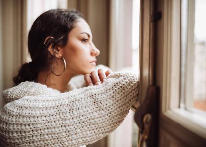 Photo of pensive woman in front of the window