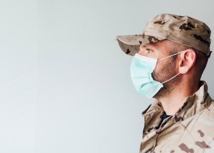 Photo of young man wearing camouflage and mask looking sideways