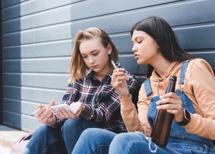 Photo of young teenage girls drinking and smoking outdoors